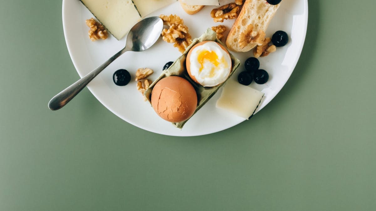A delicious assortment of breakfast items including cheese, soft boiled egg, and walnuts on a stylish plate.